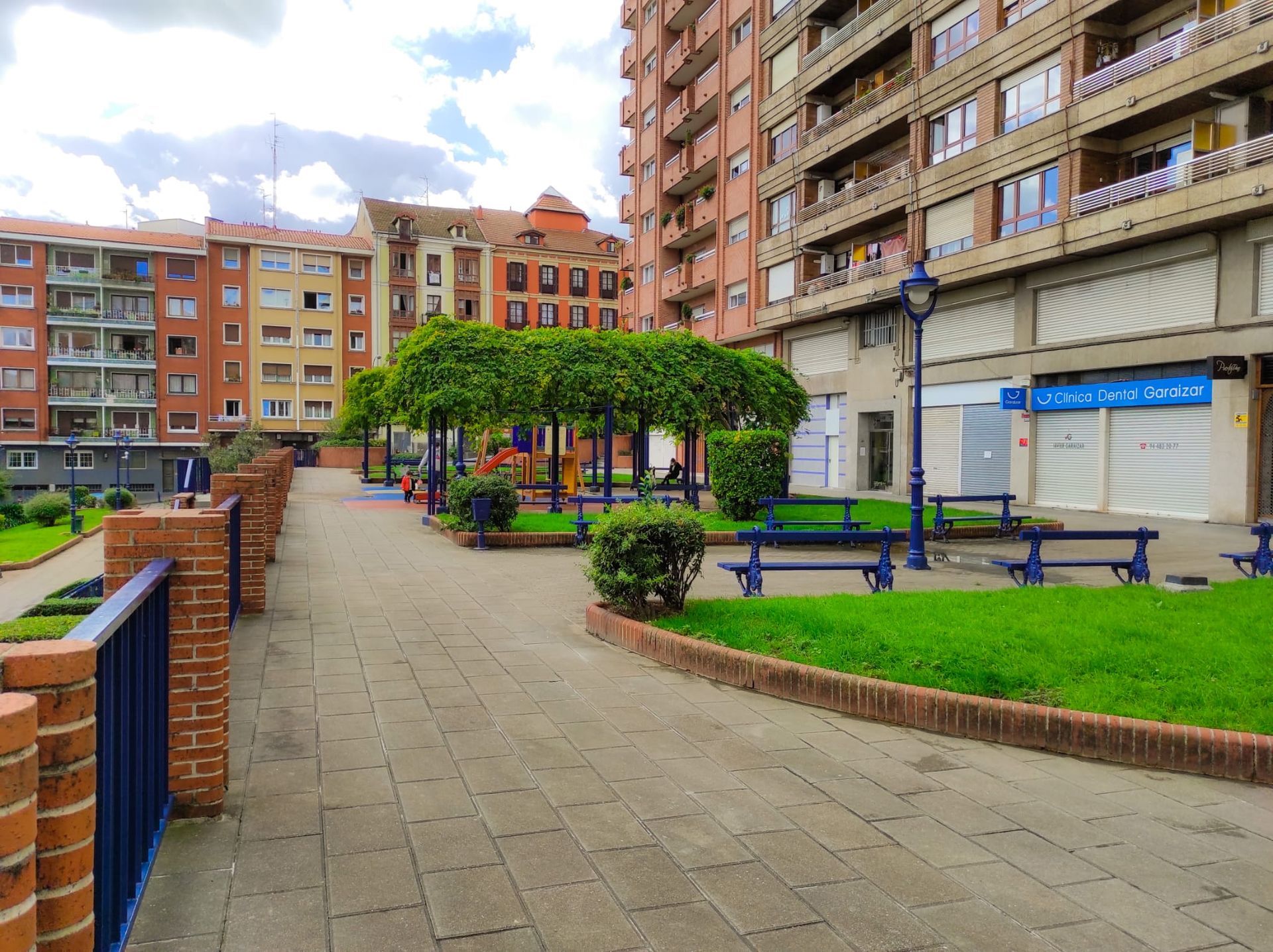Una pasarela de ladrillos que conduce a un parque rodeado de edificios altos.