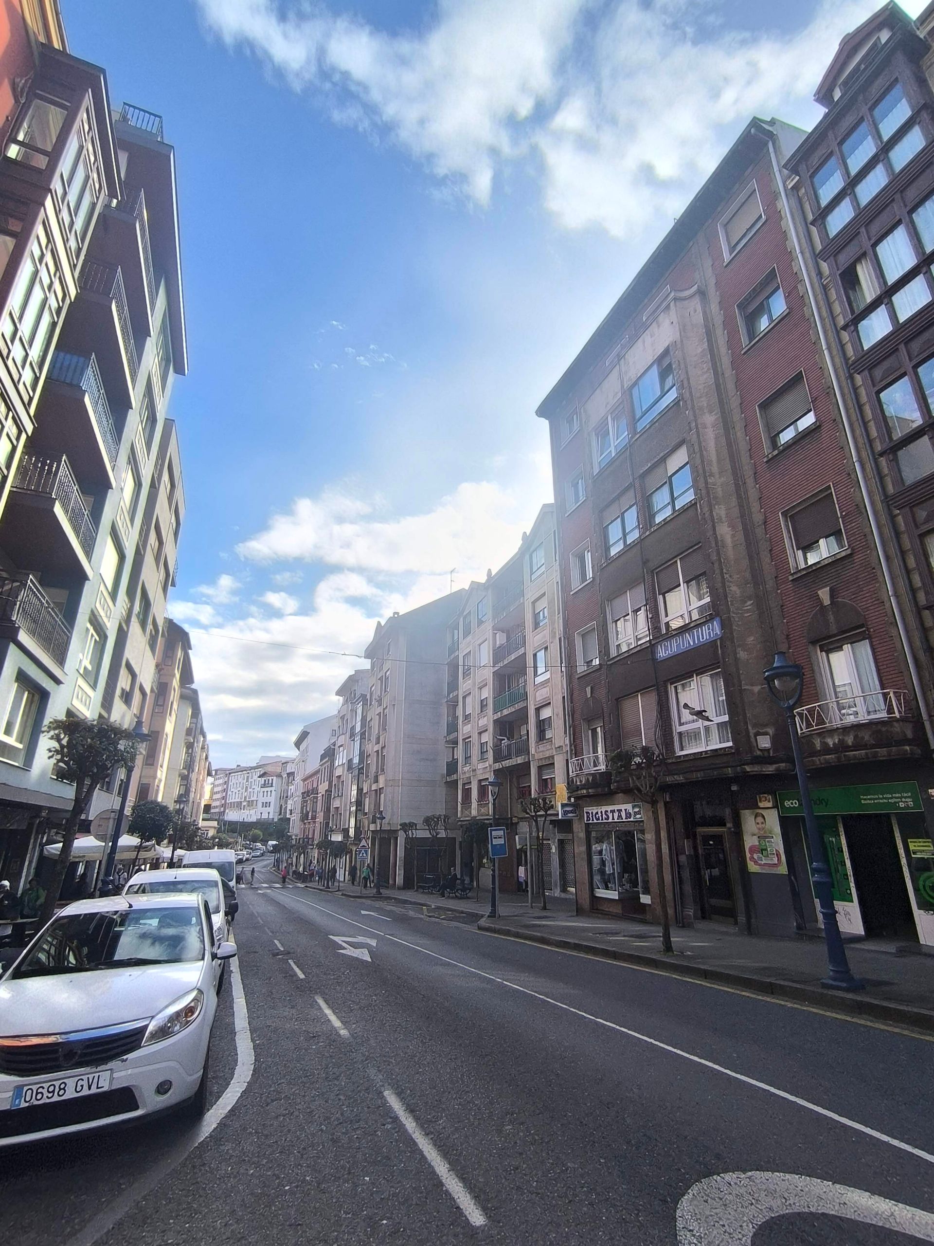 Un automóvil circula por una calle de la ciudad entre dos edificios altos.