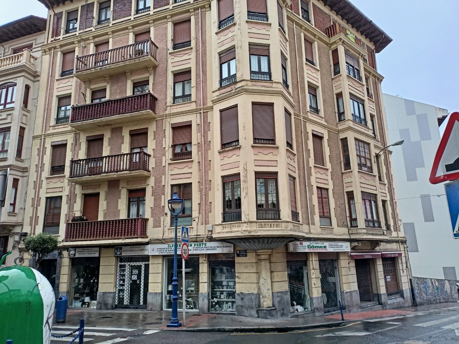 Un gran edificio con muchas ventanas está situado en la esquina de una calle.
