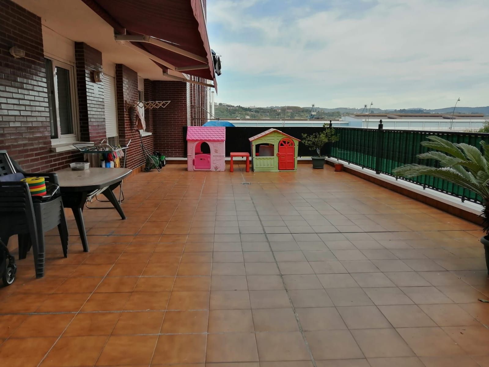 Un patio con mesa y sillas y una casita de juegos rosa.