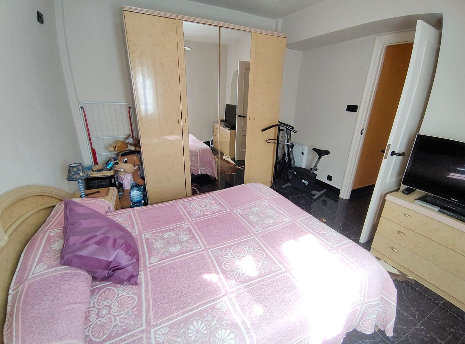 Un dormitorio con una cama, una cómoda y una televisión.