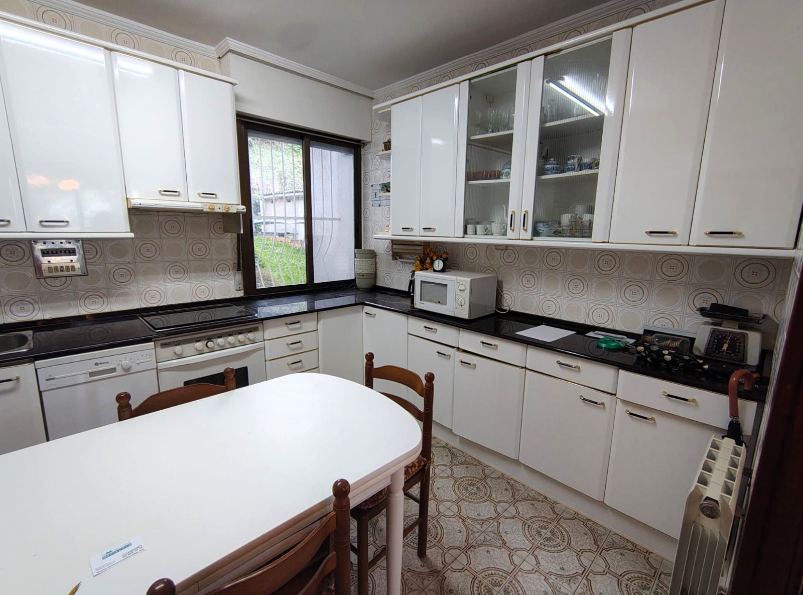 Una cocina con gabinetes blancos, una mesa y sillas.