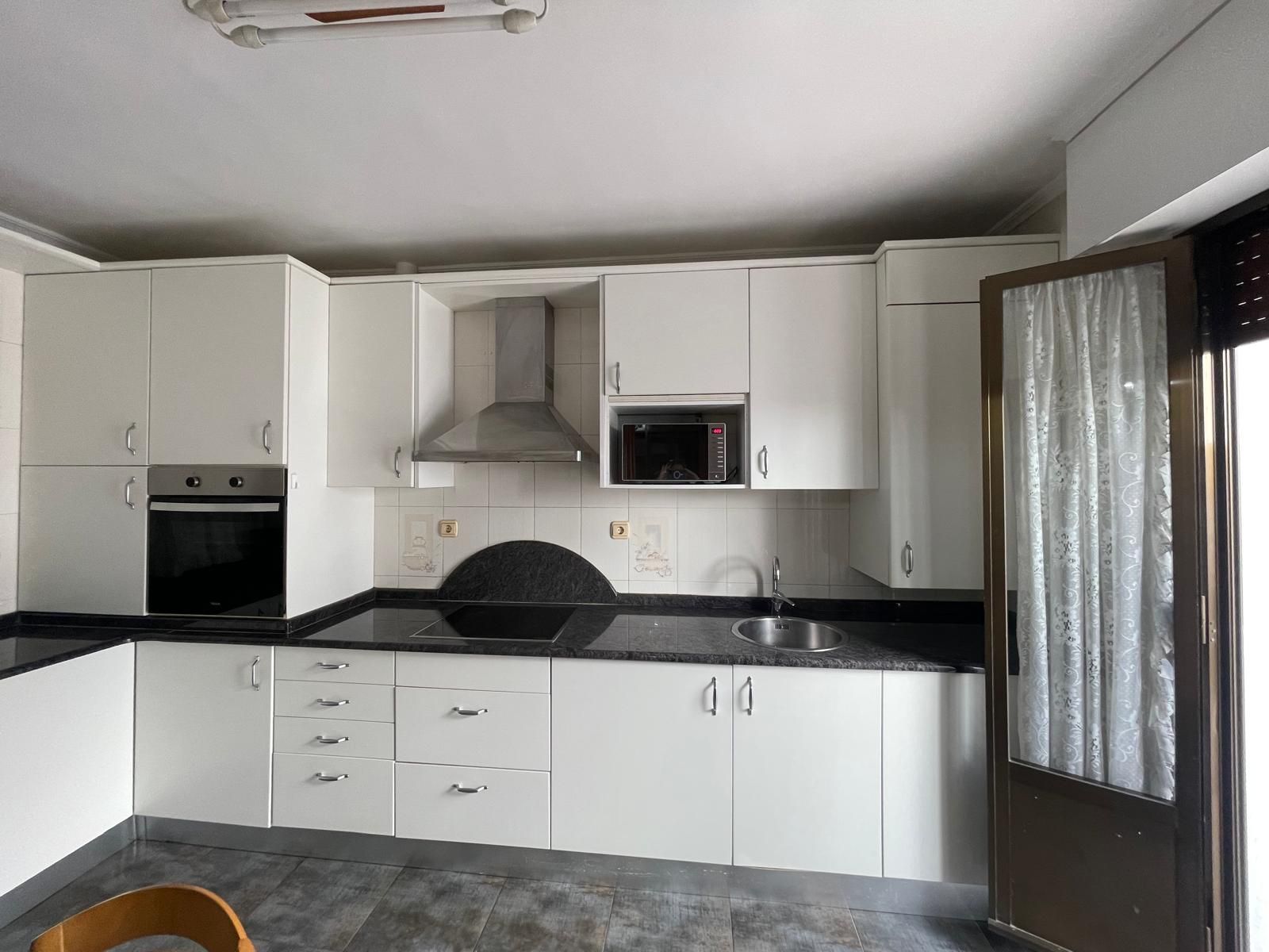 Una cocina con gabinetes blancos y encimeras negras.