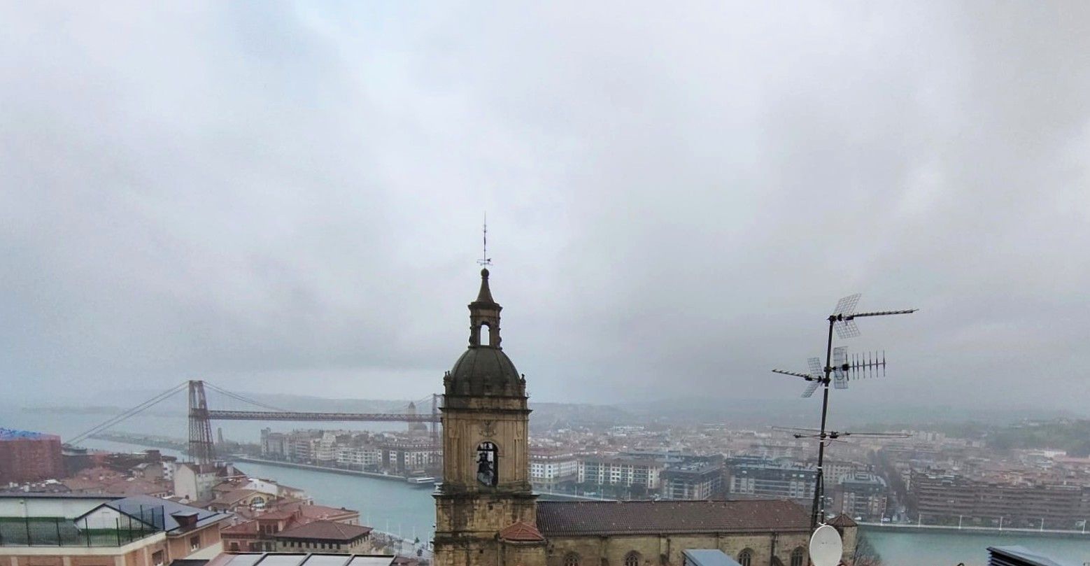 Una vista aérea de una ciudad con una torre de reloj en primer plano y un puente en el fondo.