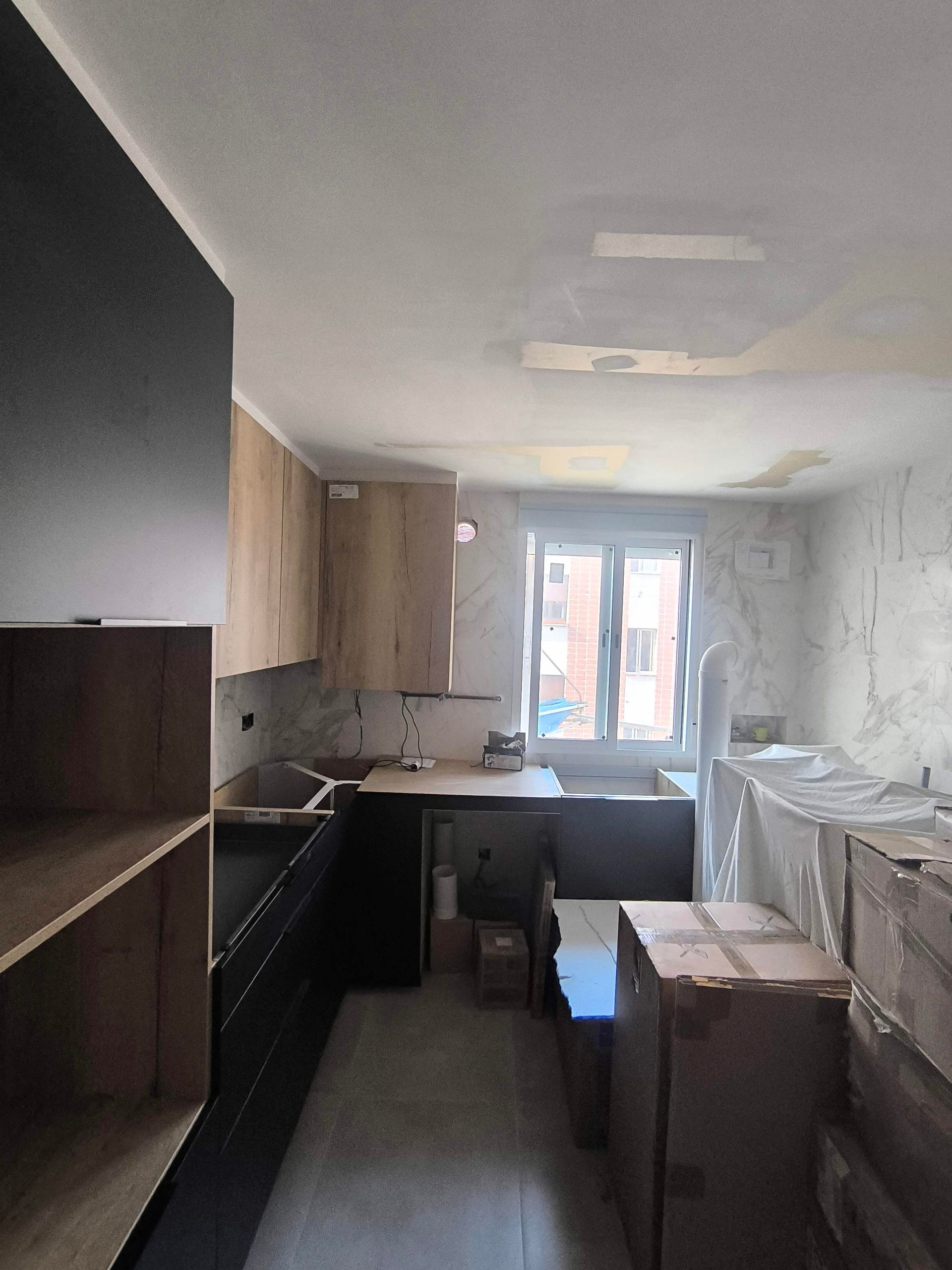 Una cocina con armarios de madera y cajas en el suelo.