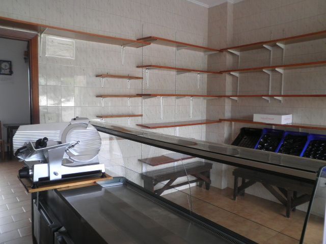 Una habitación vacía con estantes y una cortadora de carne.