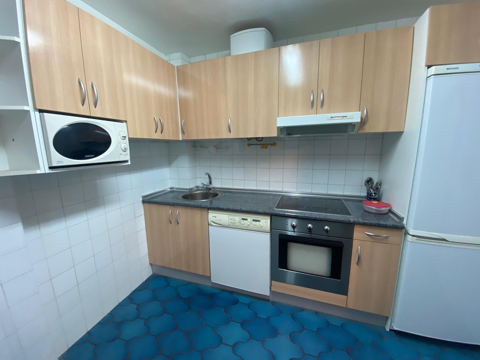 Una cocina con gabinetes de madera, una estufa, un refrigerador y un microondas.