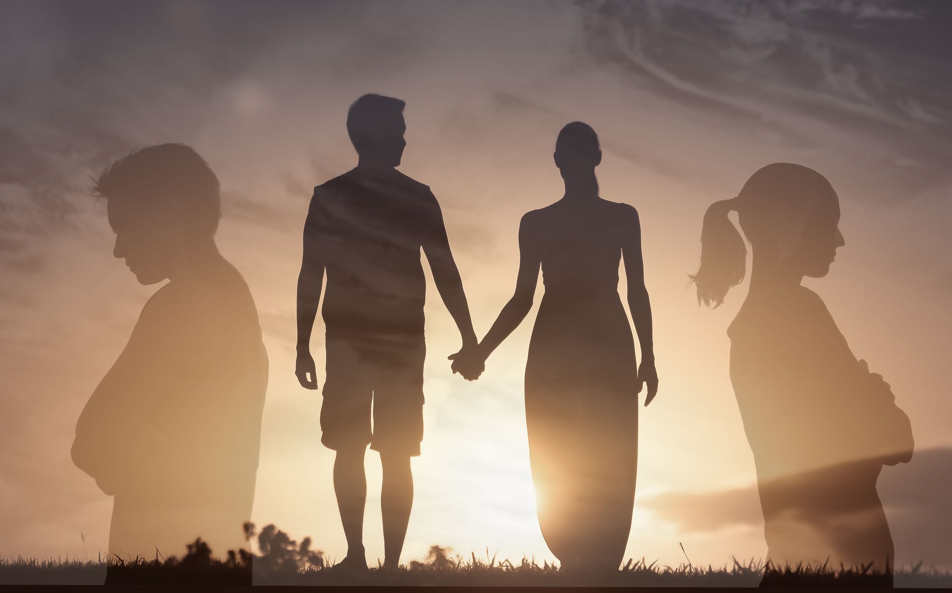 Silhouette d'un couple se tenant la main au coucher du soleil, avec des profils légèrement estompés en arrière-plan.