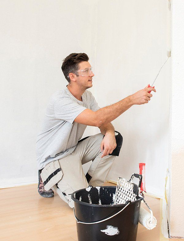 Professionnel en train de peindre un mur intérieur à l'aide d'un rouleau
