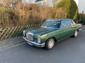 Ein grüner Mercedes Benz steht am Straßenrand.