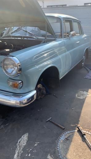 Ein blaues Auto mit geöffneter Motorhaube steht auf einem Parkplatz.