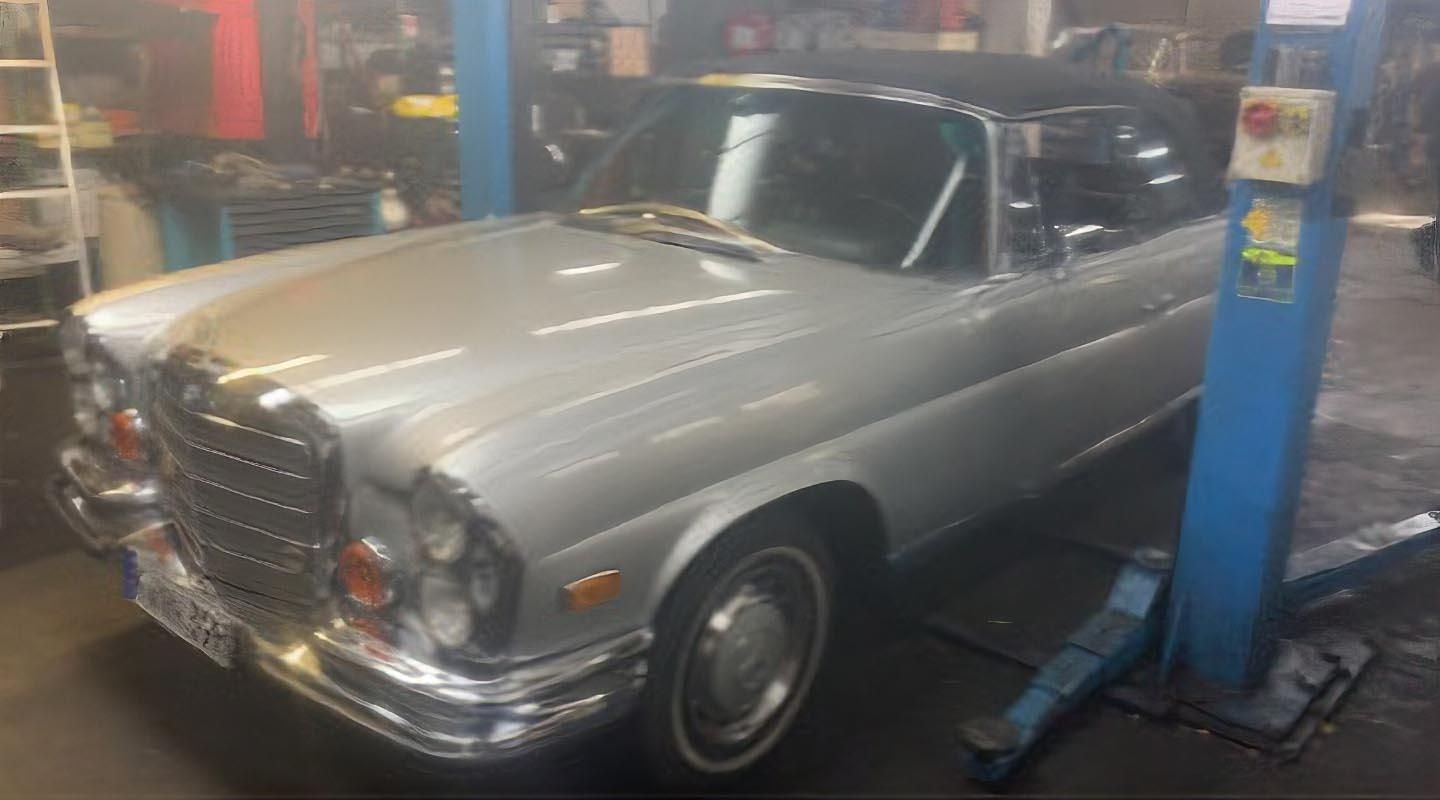 Ein silbernes Auto steht auf einer Hebebühne in einer Garage.