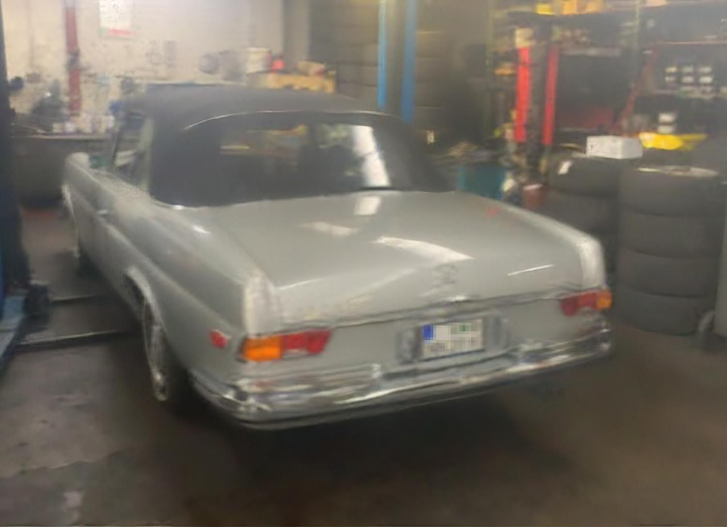 Ein silbernes Auto mit schwarzem Dach steht in einer Garage.