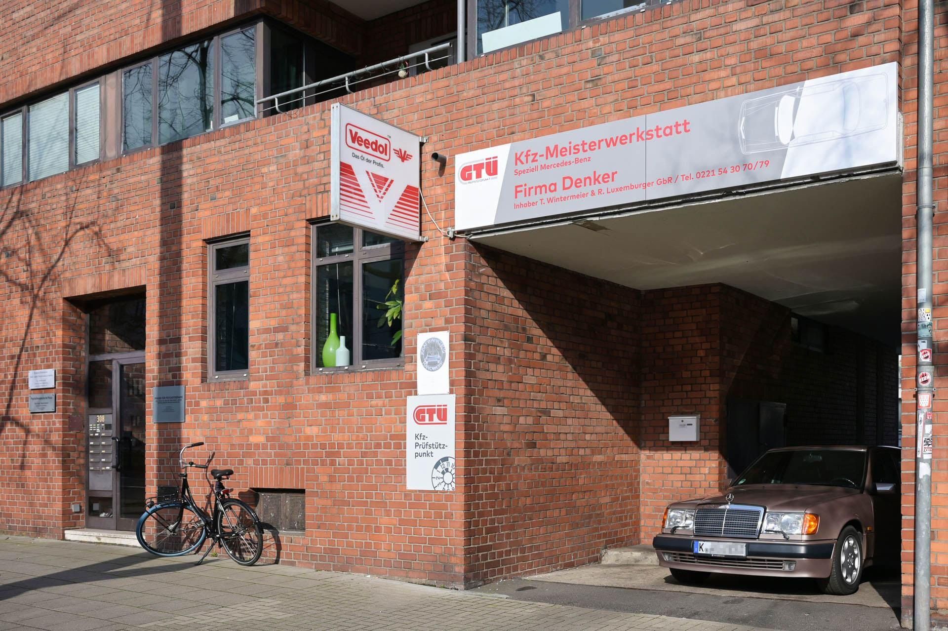 Vor einem Backsteingebäude ist ein Auto geparkt.