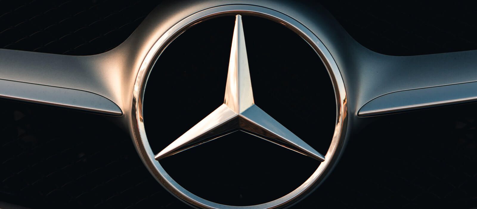 Eine Nahaufnahme eines Mercedes-Benz-Logos auf schwarzem Hintergrund
