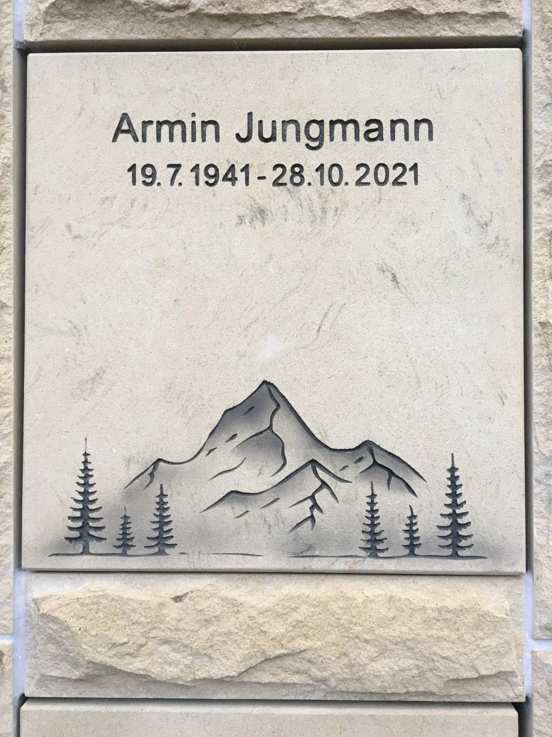 Ein Grabstein für Armin Jungmann mit einem Berg und Bäumen darauf