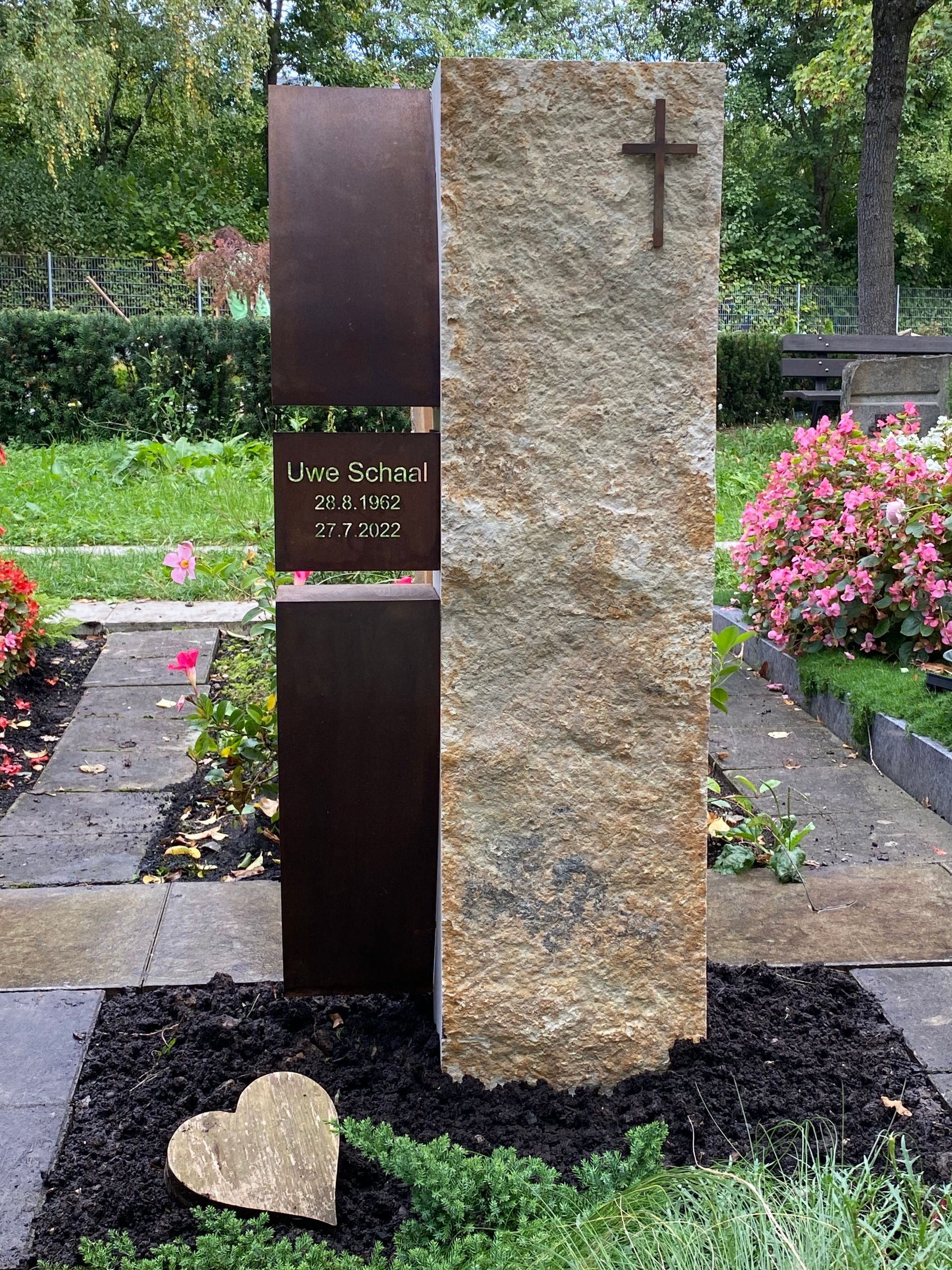 Ein Grabstein mit einem Kreuz darauf auf einem Friedhof.