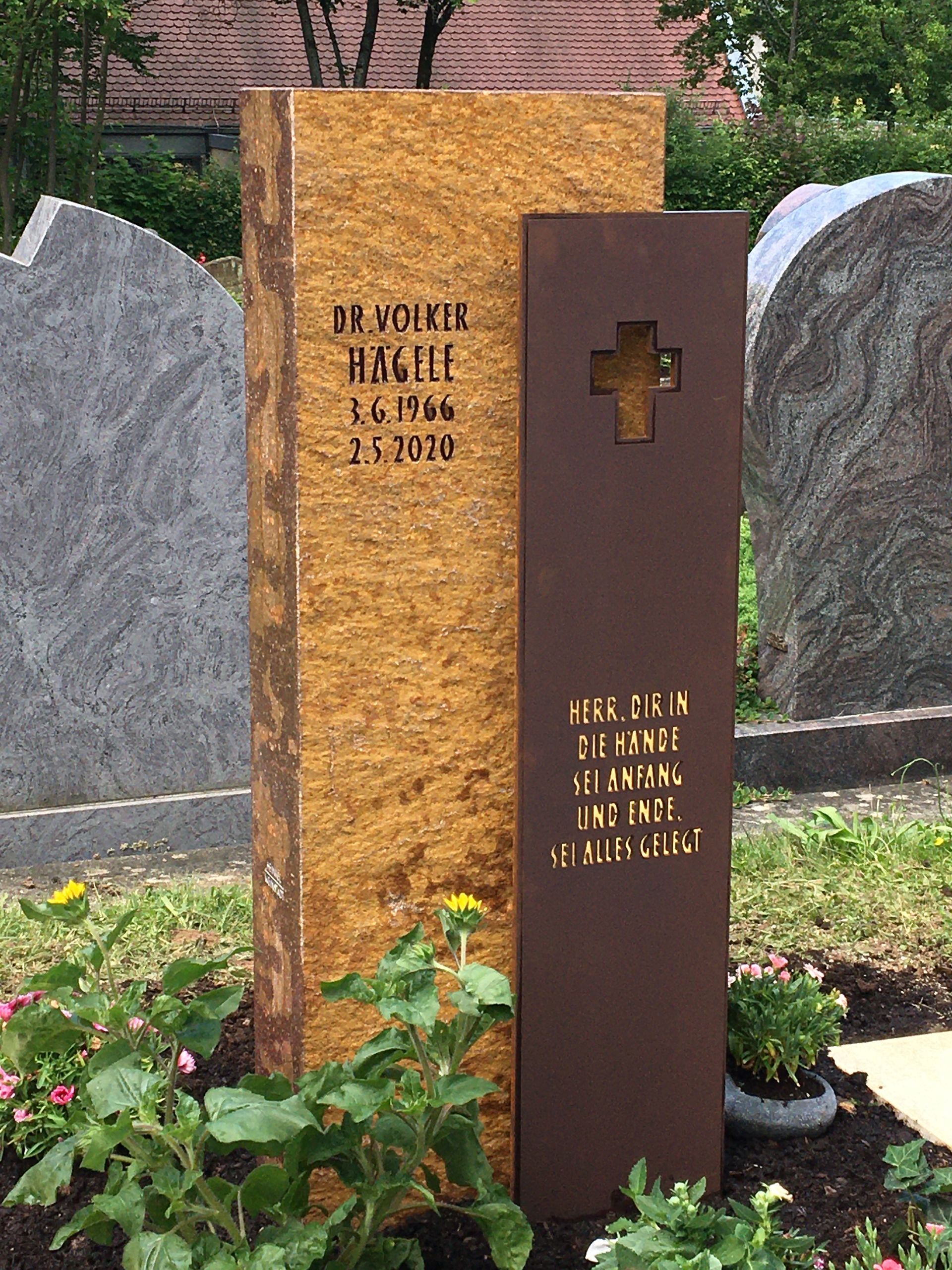 Ein Grabstein mit einem Kreuz darauf auf einem Friedhof.