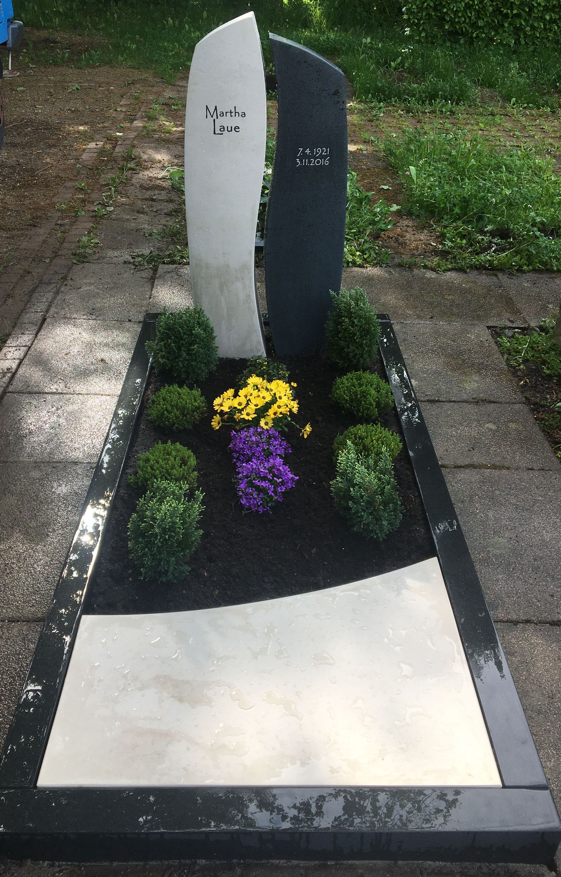 Ein Grab mit violetten und gelben Blumen darauf