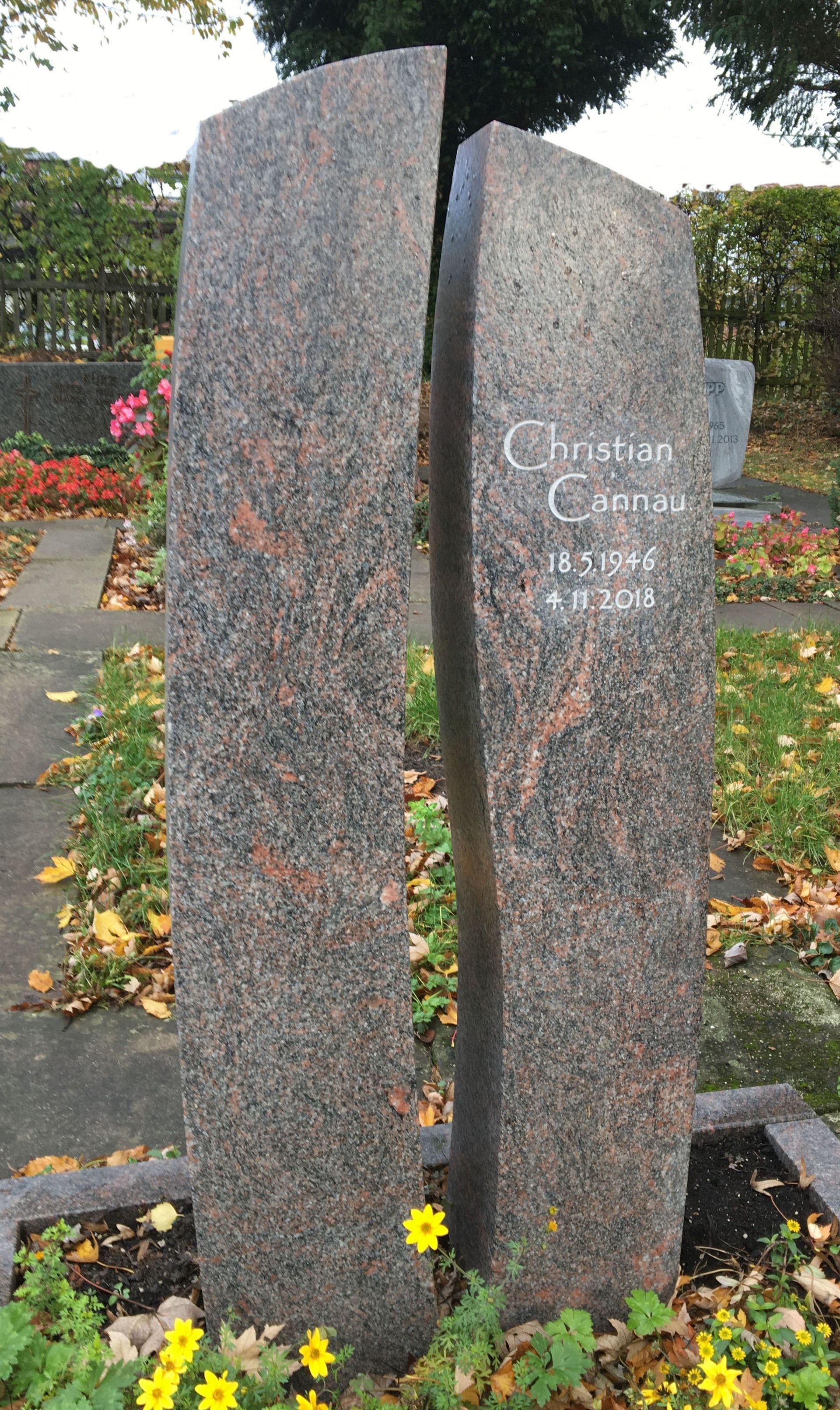 Ein Grabstein auf einem Friedhof mit einem Baum im Hintergrund.