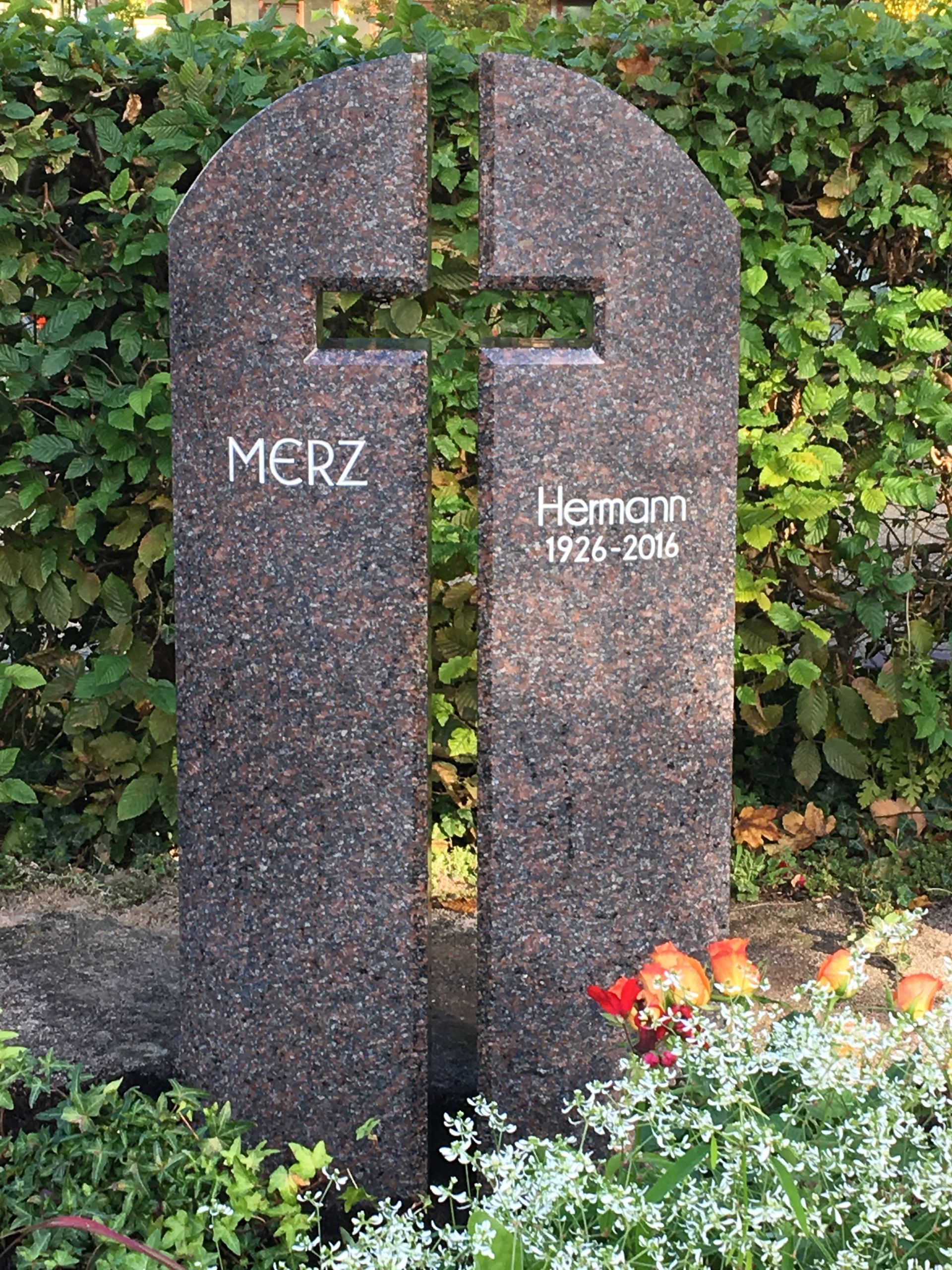 Ein Grabstein mit einem Kreuz darauf auf einem Friedhof.