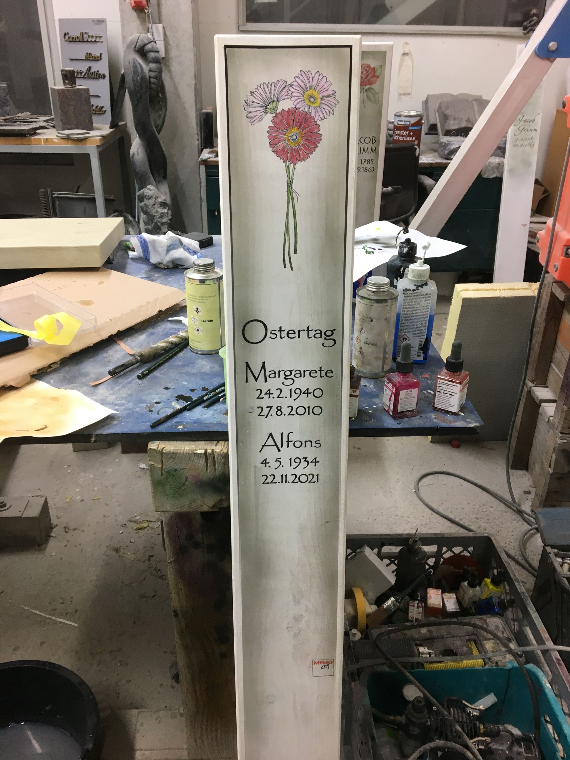 Auf einem Tisch steht eine weiße Tafel mit einer Blume darauf.