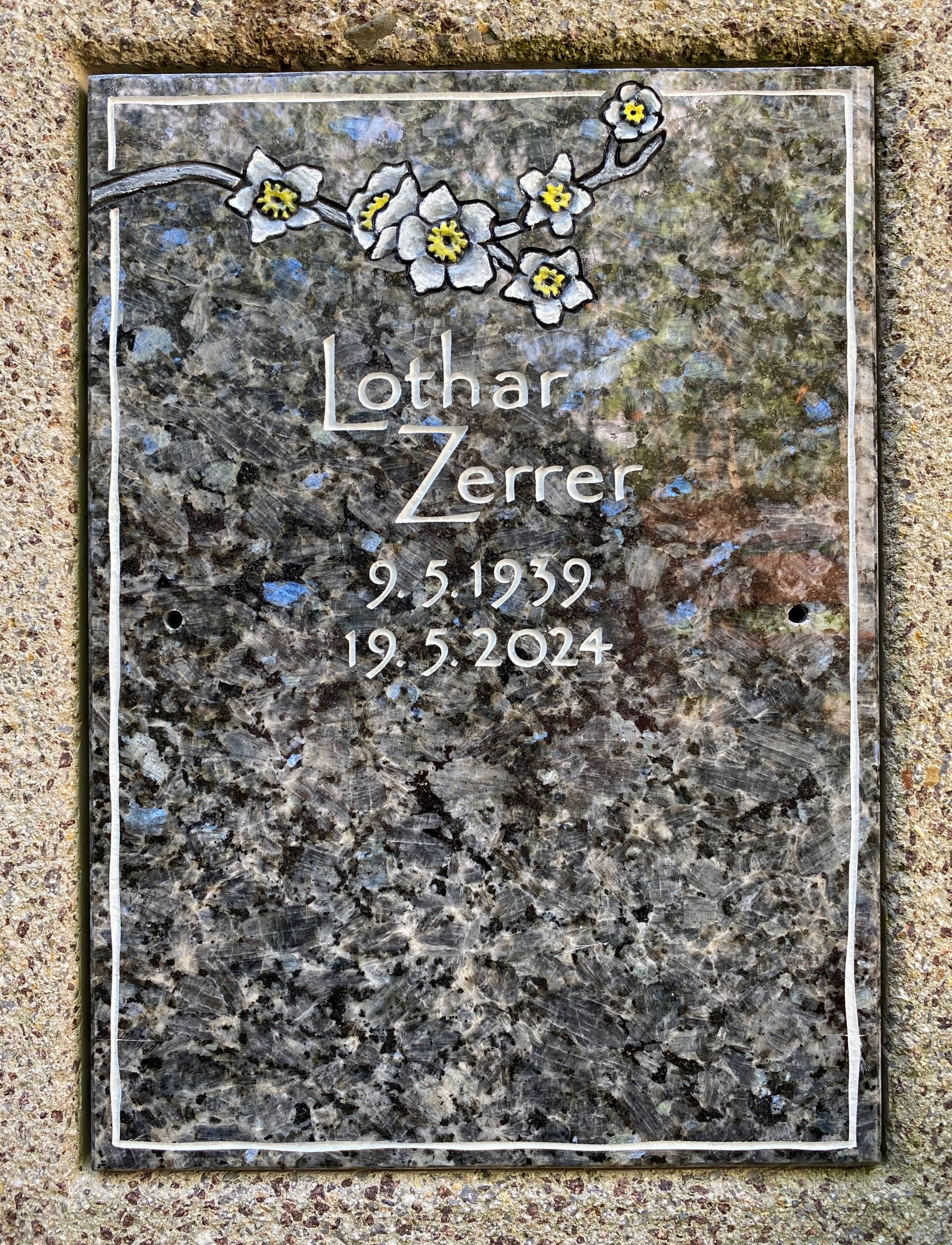 Ein Grabstein für eine Person mit Blumen darauf.