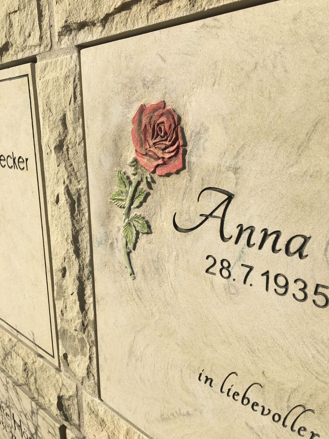 Ein Grabstein für Anna mit einer roten Rose darauf