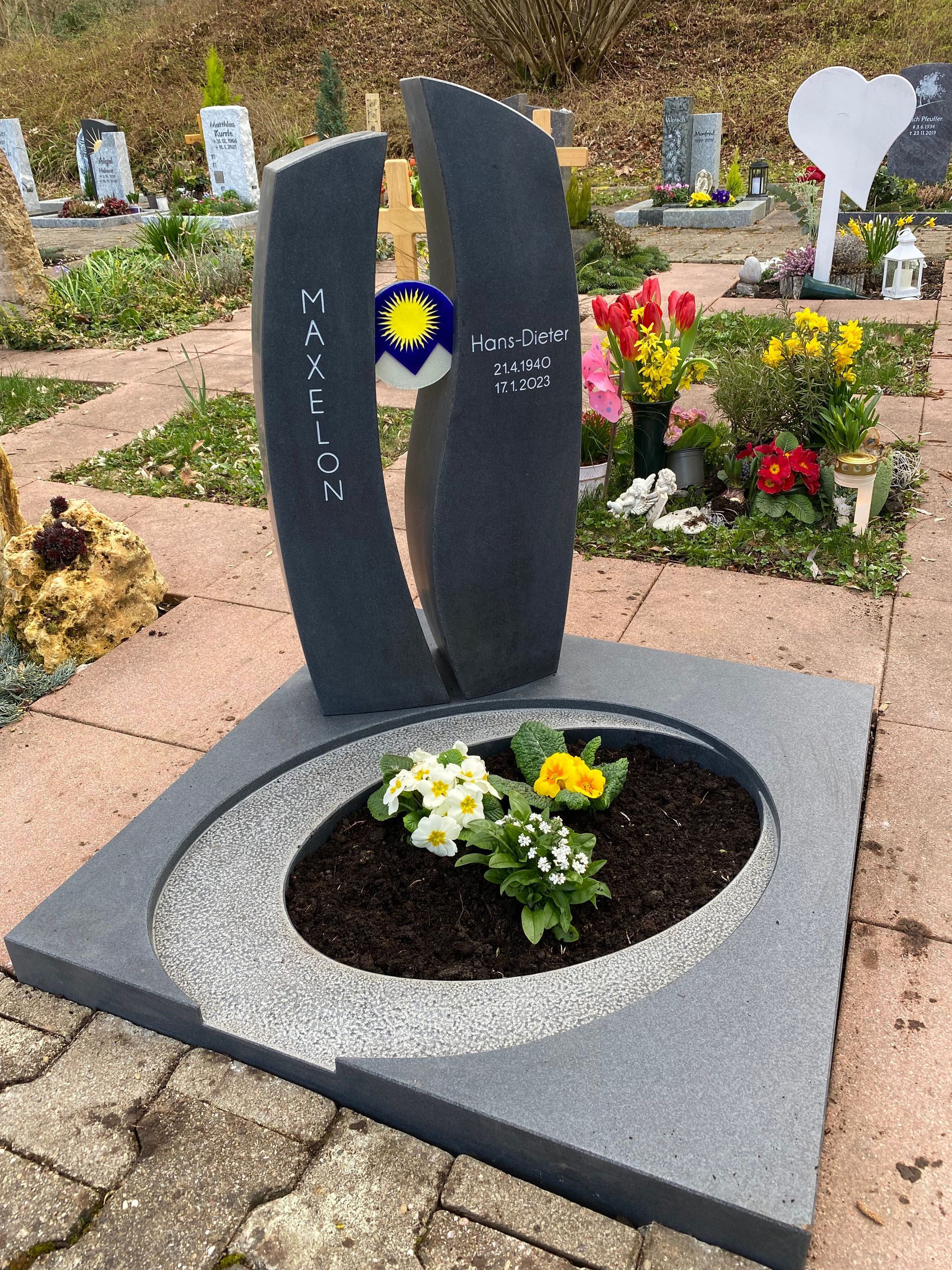 Ein Grab auf einem Friedhof mit Blumen darin.