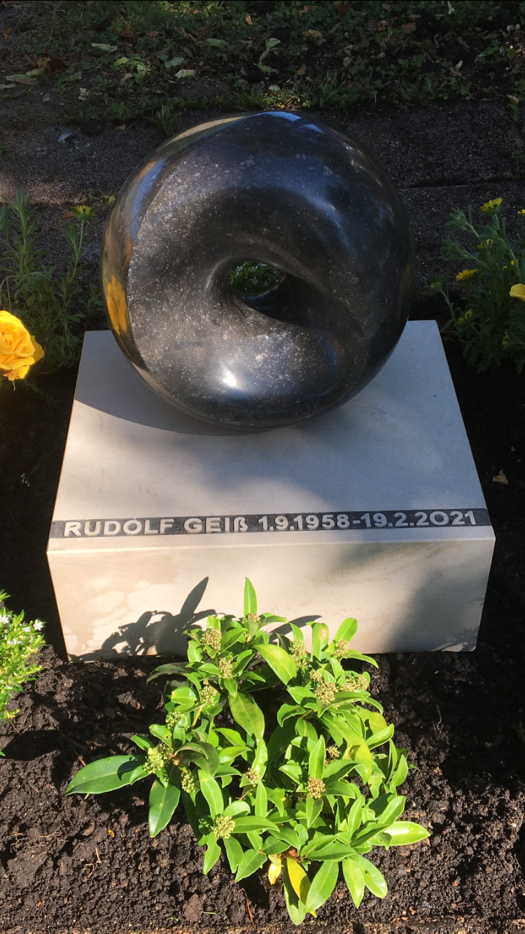 Auf einem Grab sitzt eine Donut-Statue.