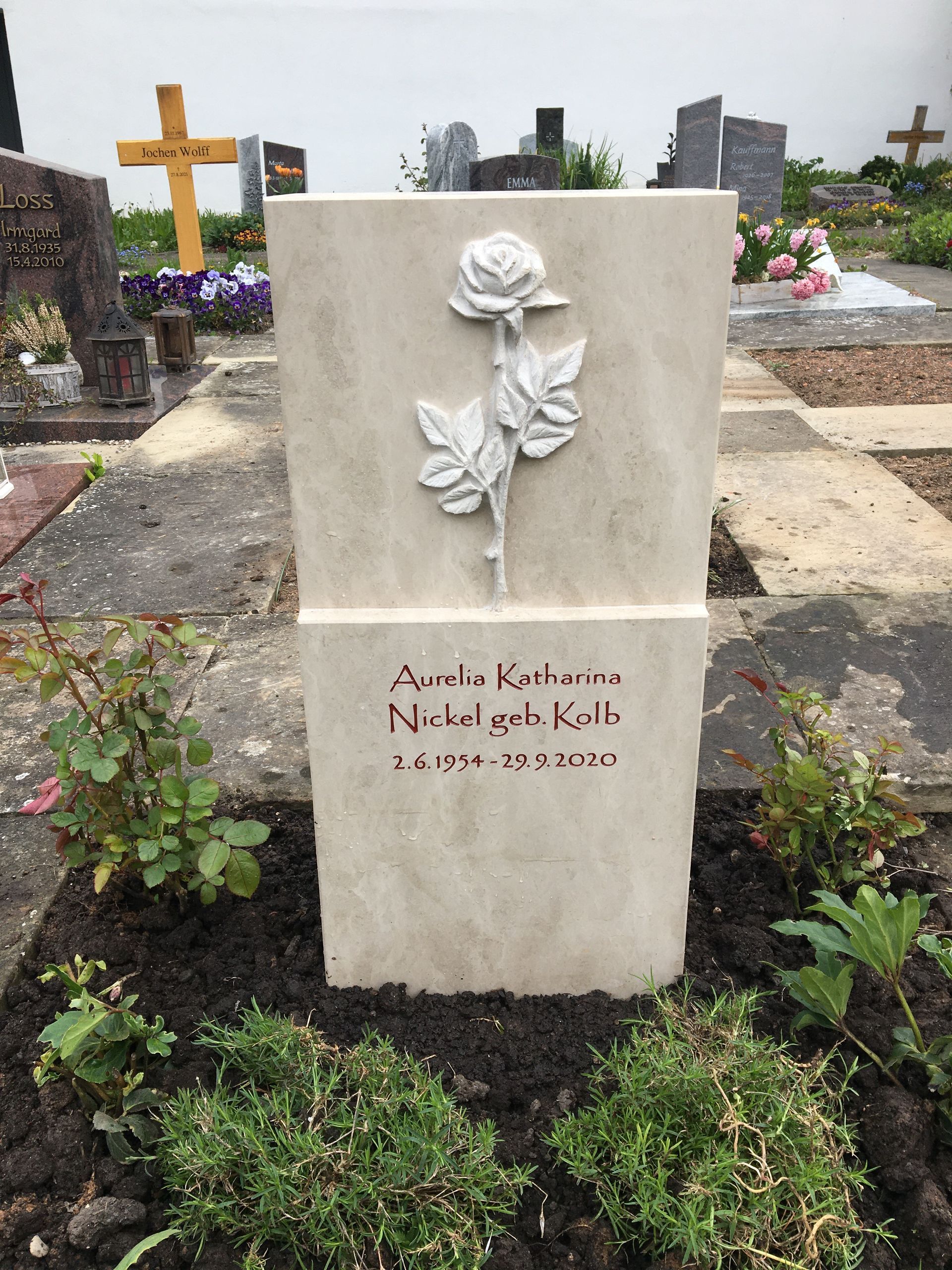 Ein Grabstein mit einer Rose darauf auf einem Friedhof.