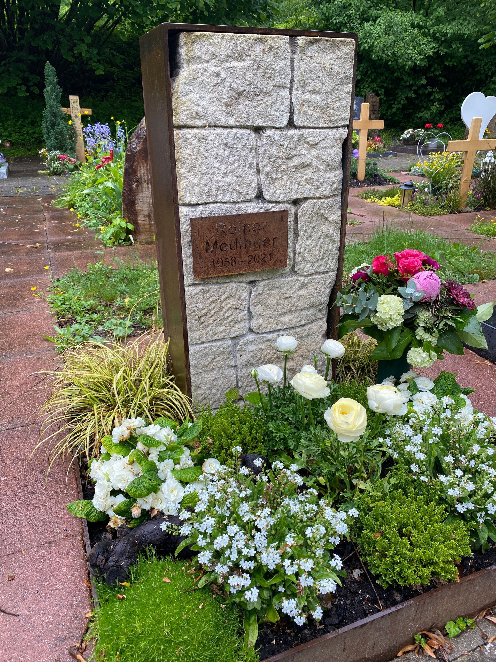 Ein Grab mit Blumen und einem Kreuz auf einem Friedhof.