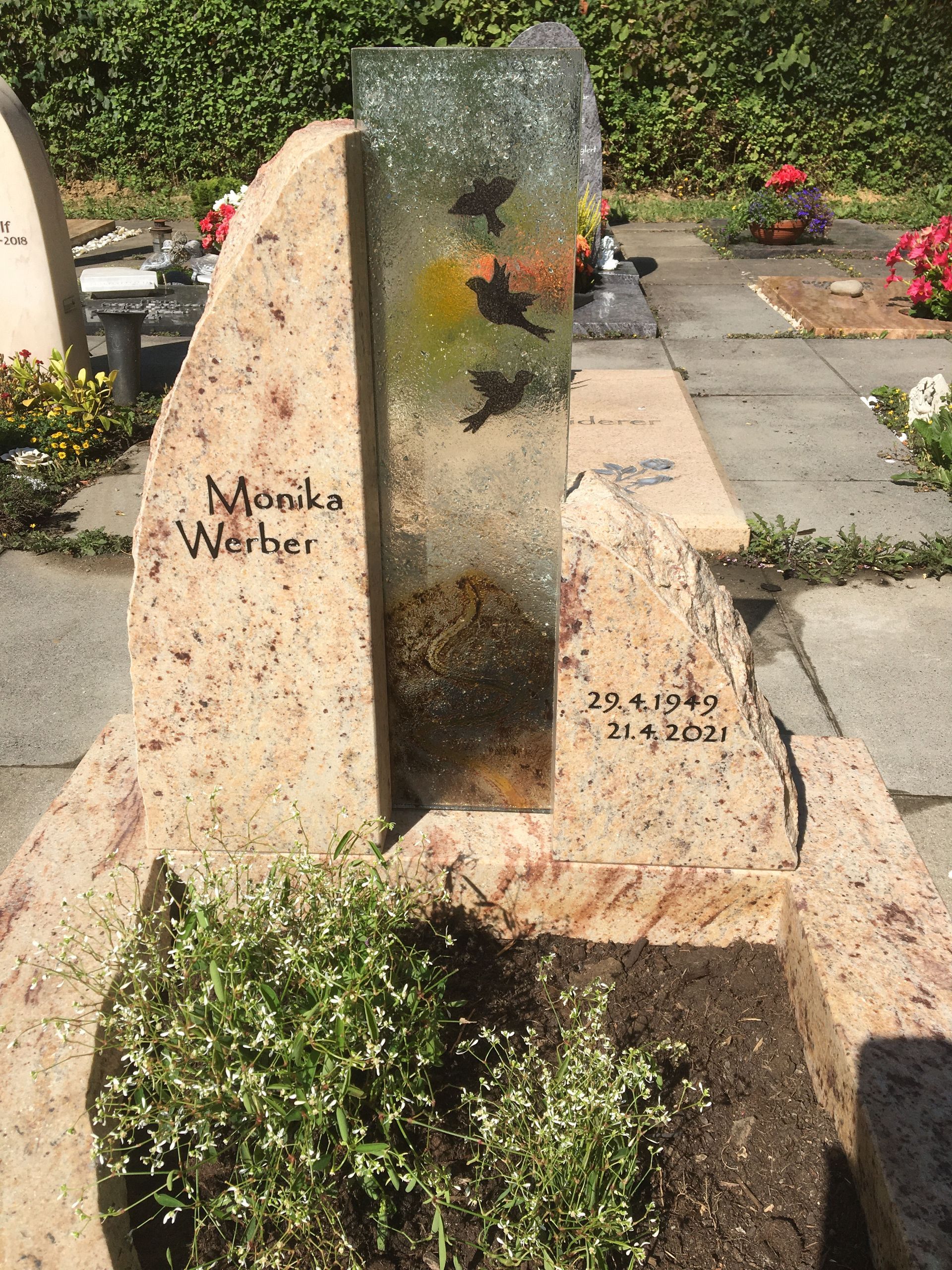Ein Grabstein mit einer Glasskulptur darauf auf einem Friedhof.