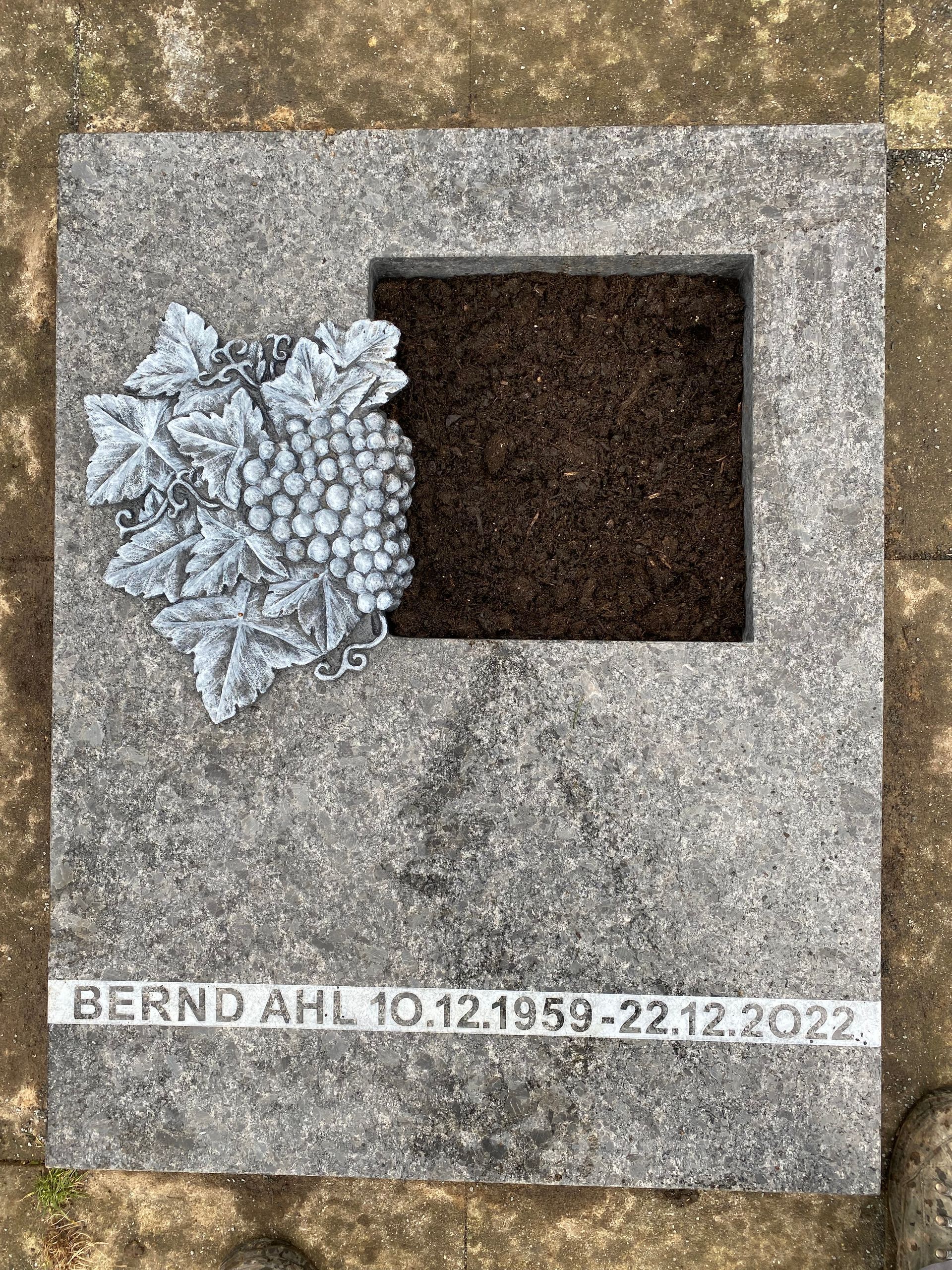 Ein Grabstein mit einem Herz und Trauben darauf.