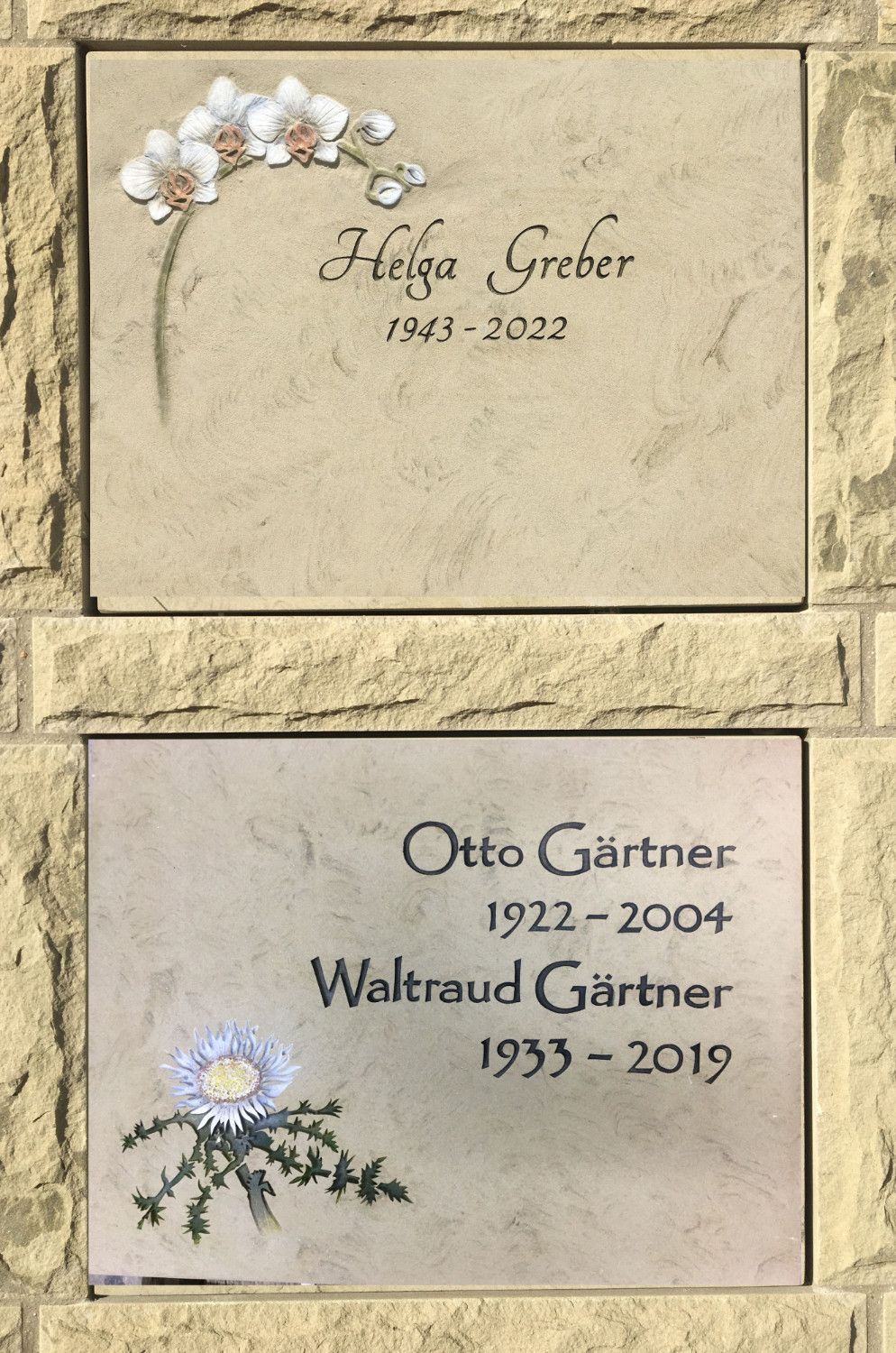 Ein paar Plaketten an einer Wand, auf denen Helga Greber und Otto Gartner stehen