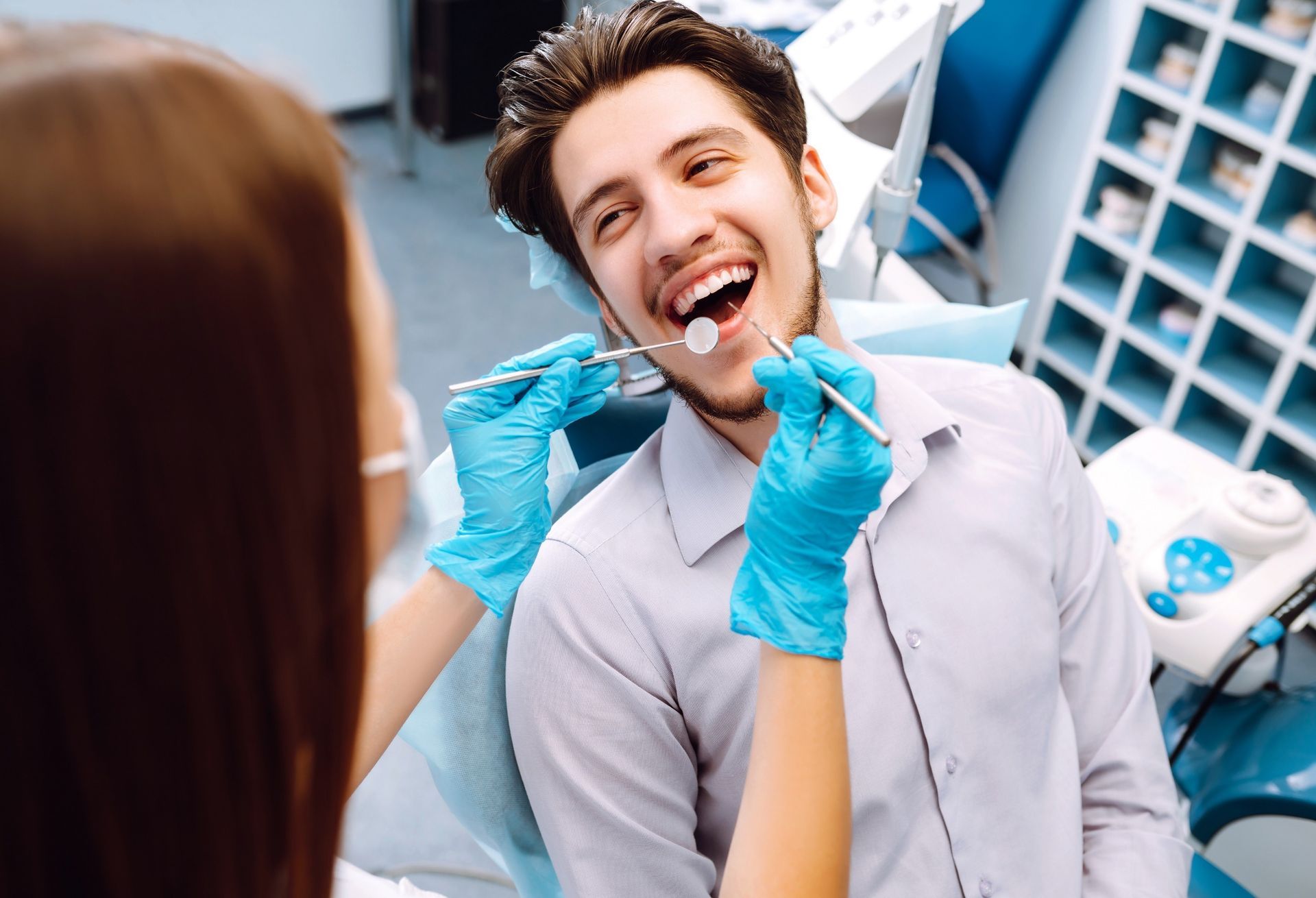Un hombre está sentado en una silla dental mientras una mujer le examina los dientes.