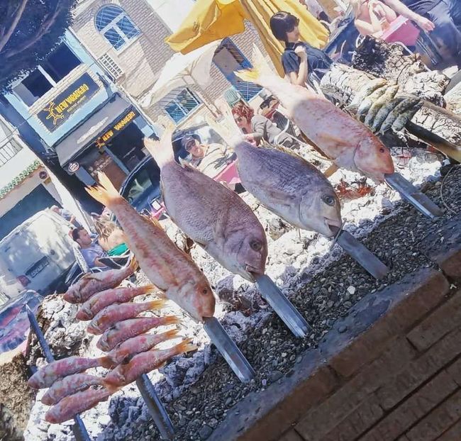Varios peces se están cocinando en palitos frente a un edificio que dice estrella