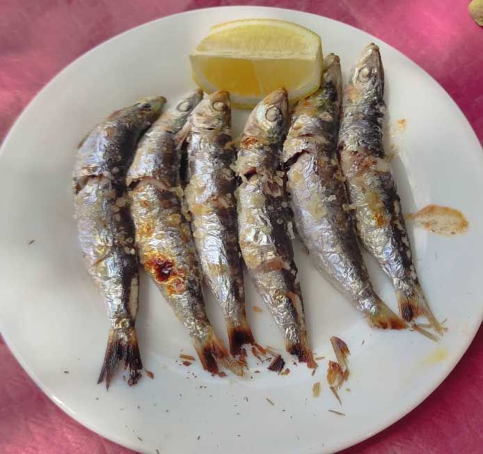 Un plato blanco cubierto con pescado y una rodaja de limón.