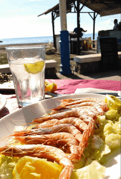 Un plato de camarones y un vaso de agua sobre una mesa.