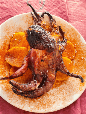 Un plato de comida con un pulpo y patatas encima.