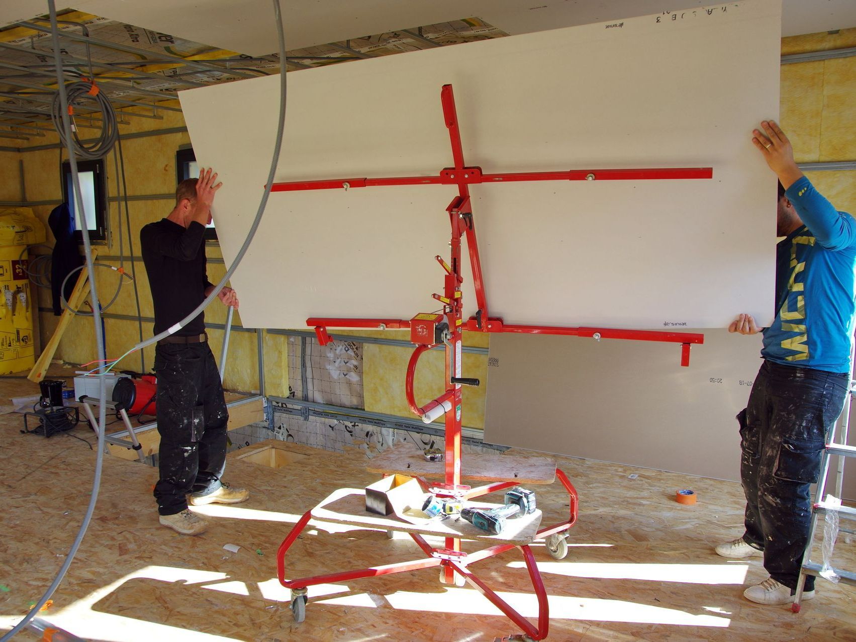 Deux ouvrier manipulant une cloison pour faux plafond