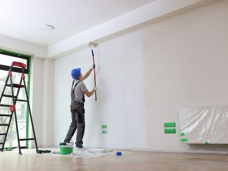 Ouvrirer qui peint un mur avec un rouleau à manche
