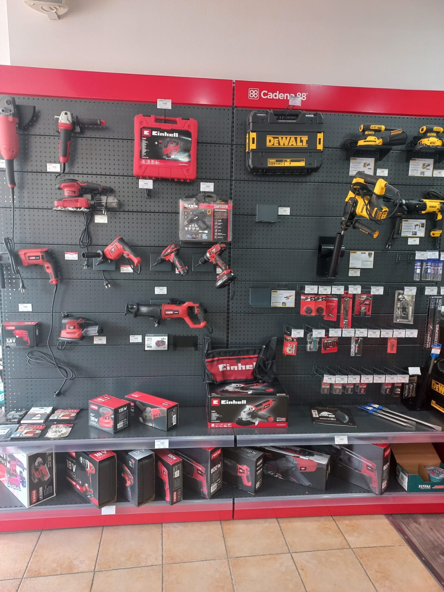 Pinceles y materiales expuestos en una tienda. Estanterías rojas y negras, pinceles de varios tamaños y bandejas de pintura.