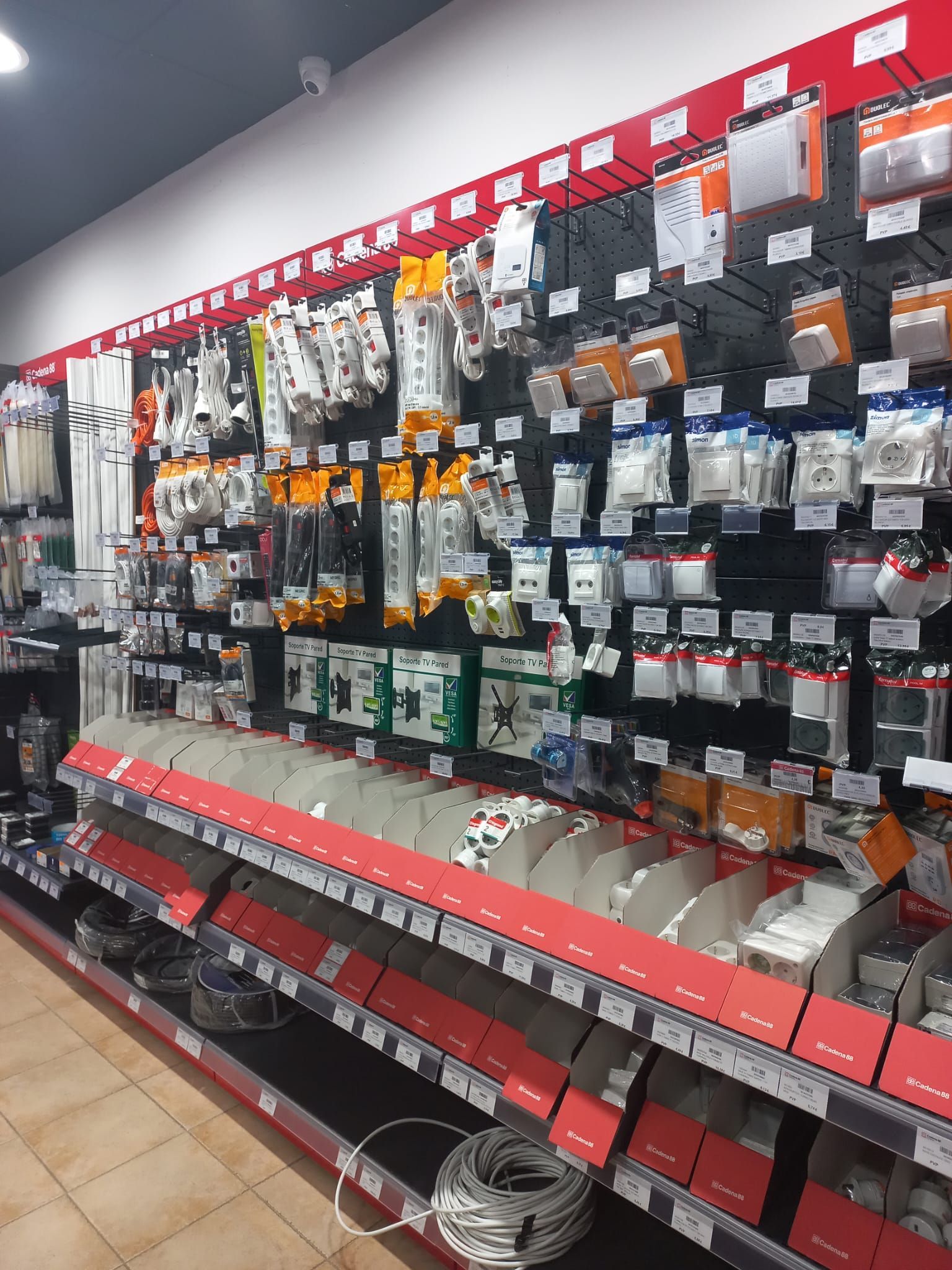 Vista interior de una tienda con filas de estantes repletos de diversos artículos para el hogar, muy iluminados.