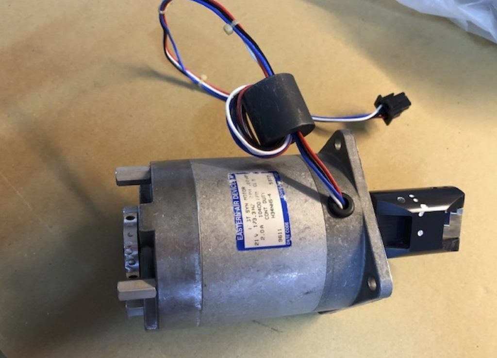 Motor eléctrico con cableado y conector negro sobre una mesa.