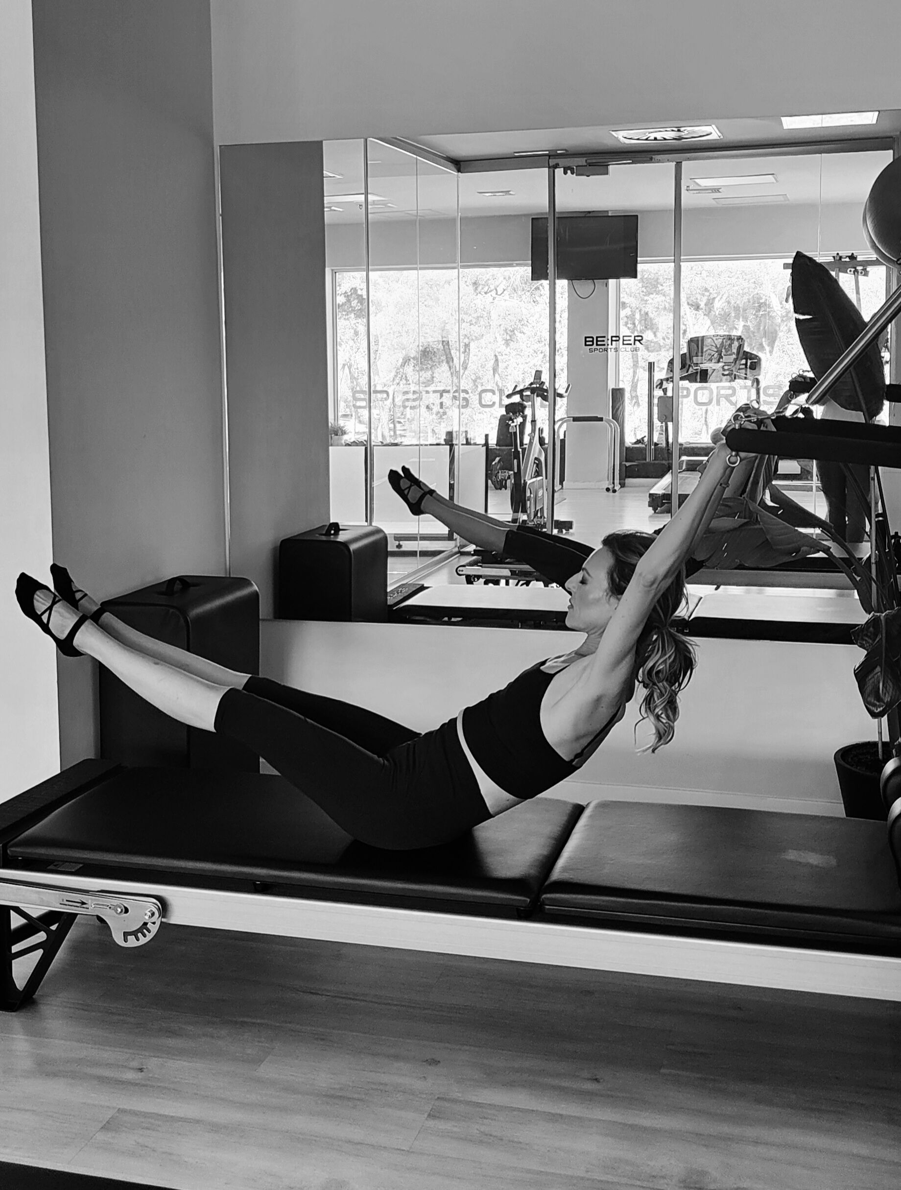 Una mujer está haciendo ejercicios en una máquina de pilates frente a un espejo.