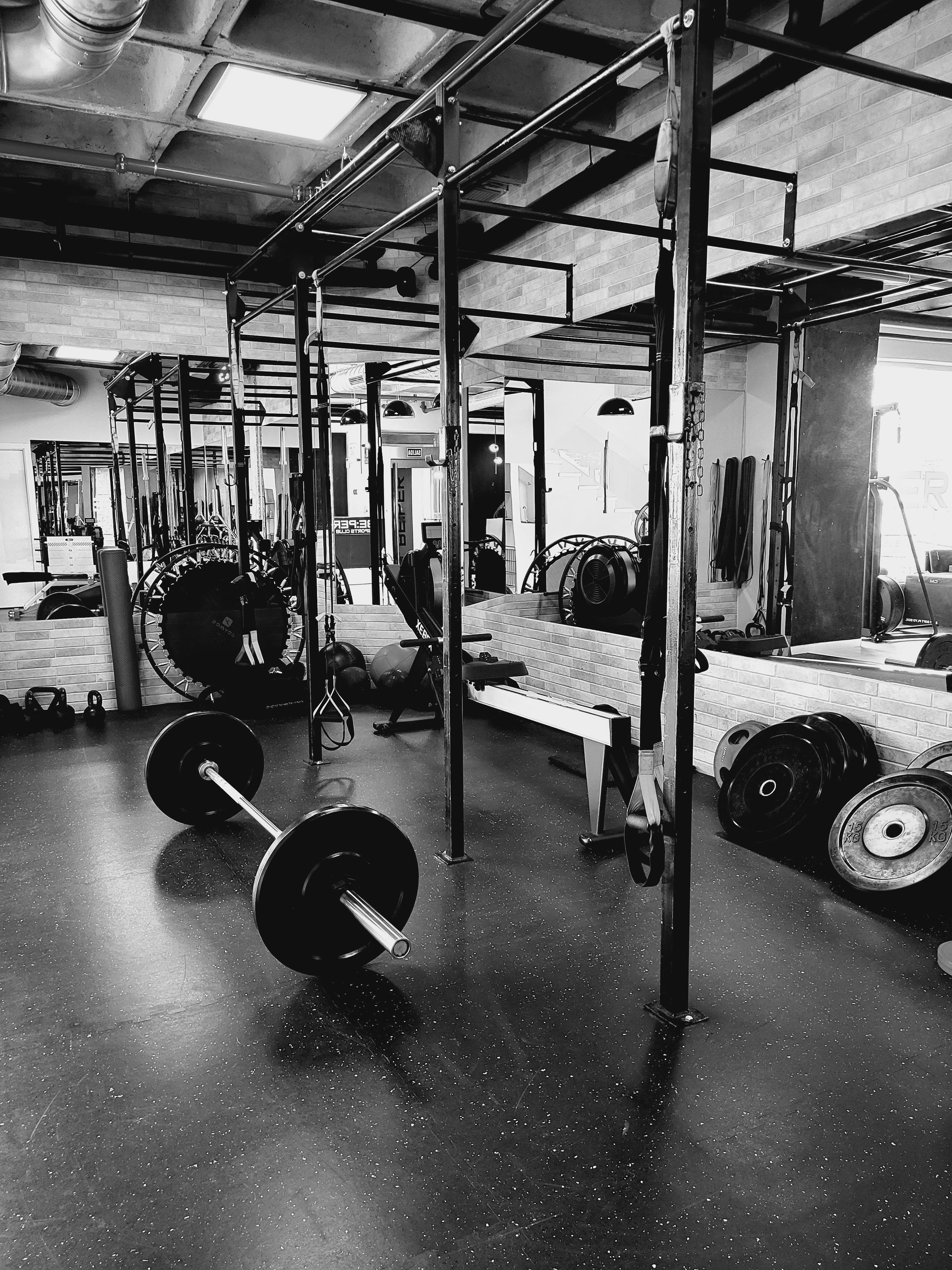 Una fotografía en blanco y negro de un gimnasio con una barra en el suelo.