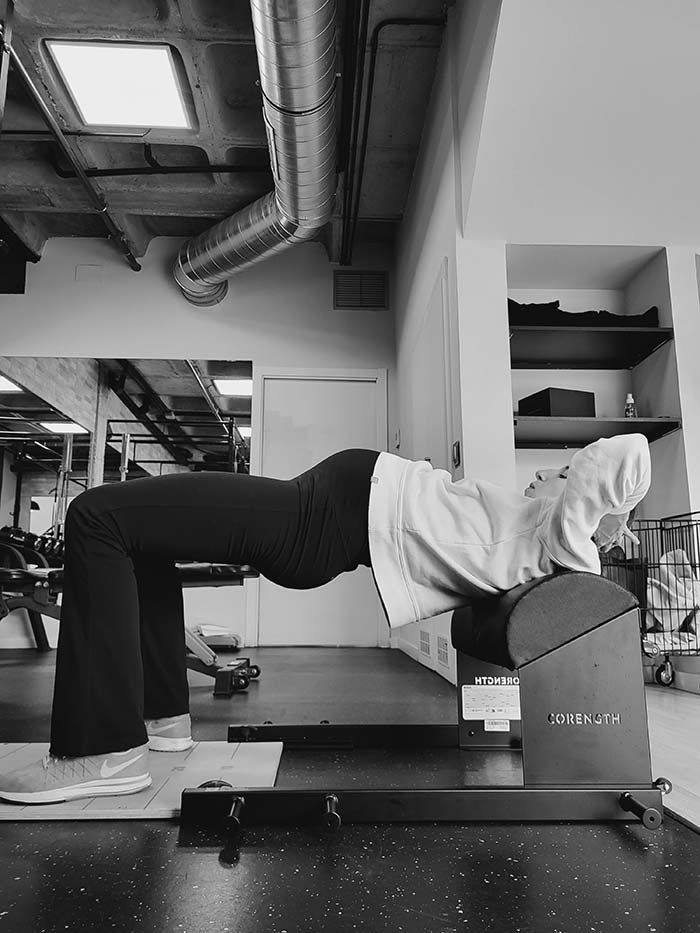 Persona realizando un ejercicio de Pilates en arco. Se arquea sobre el arco en posición de puente, con las manos detrás de la cabeza.