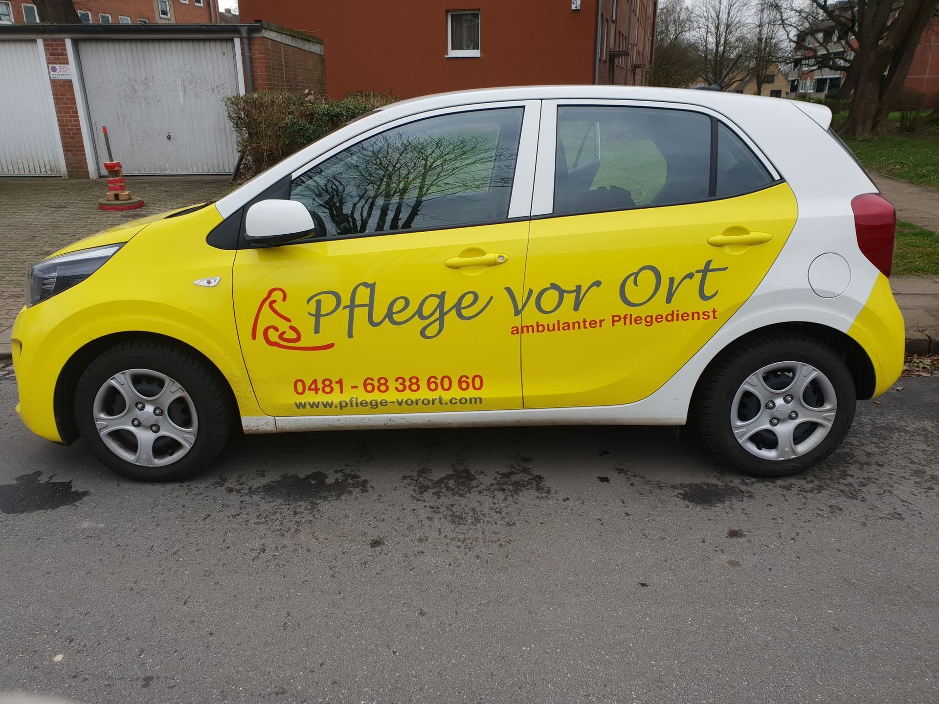 Ein gelb-weißer Pflegedienstwagen mit der Aufschrift „Pflege vor Ort“ parkt auf einer Straße.
