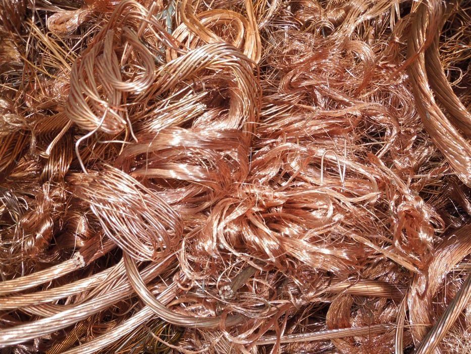 Un montón grande y desordenado de hebras de alambre de cobre peladas y brillantes, de diferentes grosores y formas de bobina.